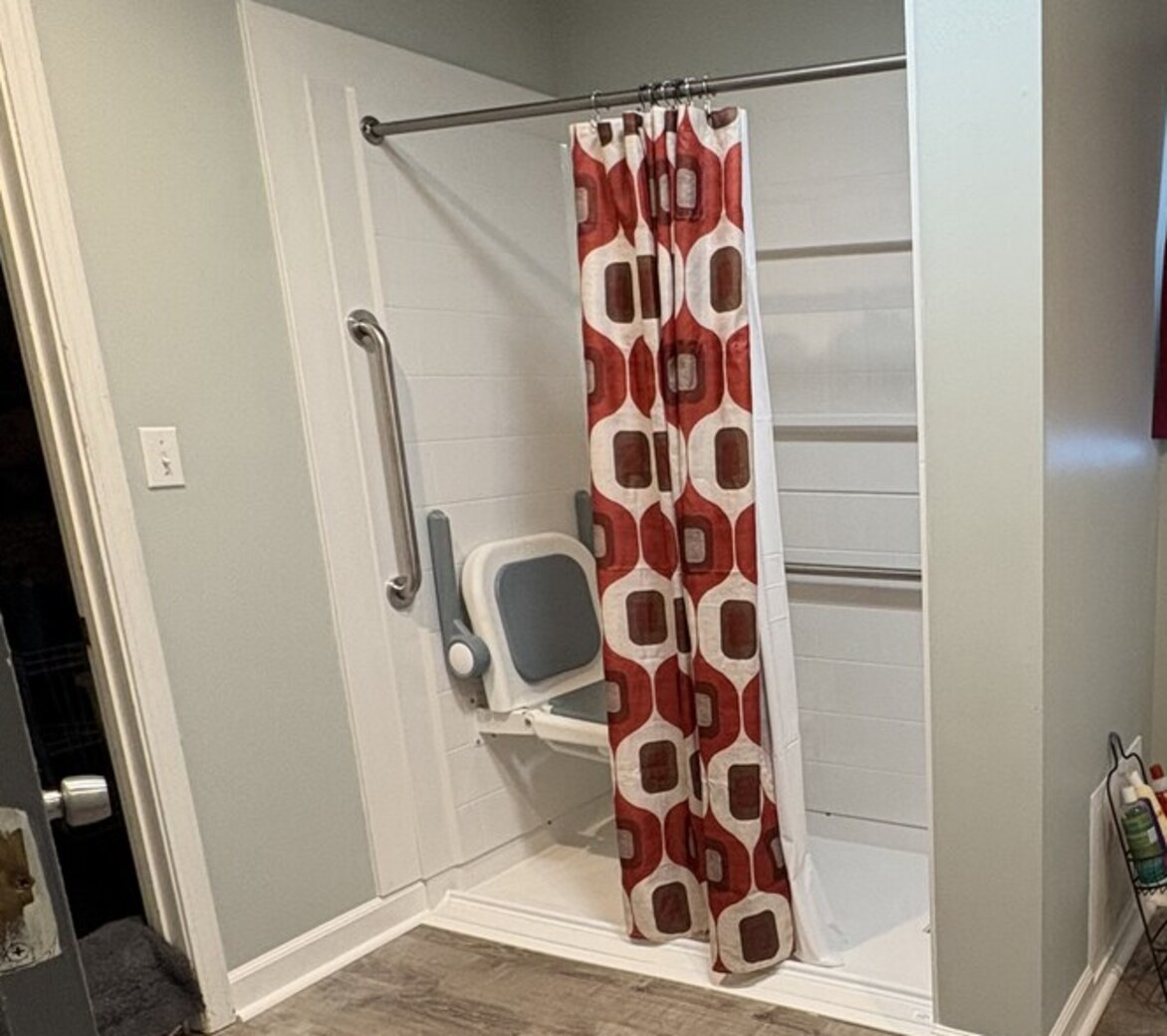Finished central Indiana bathroom with a low-threshold walk-in shower, fold-down shower seat with backrest, and anchored grab bars