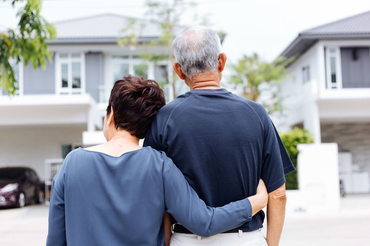 Older couple standing together outside a home