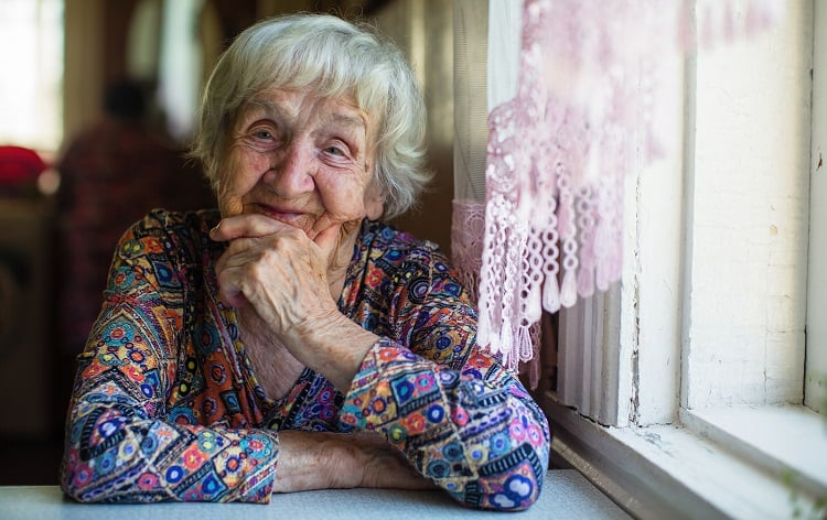 Older woman sitting beside a window at home