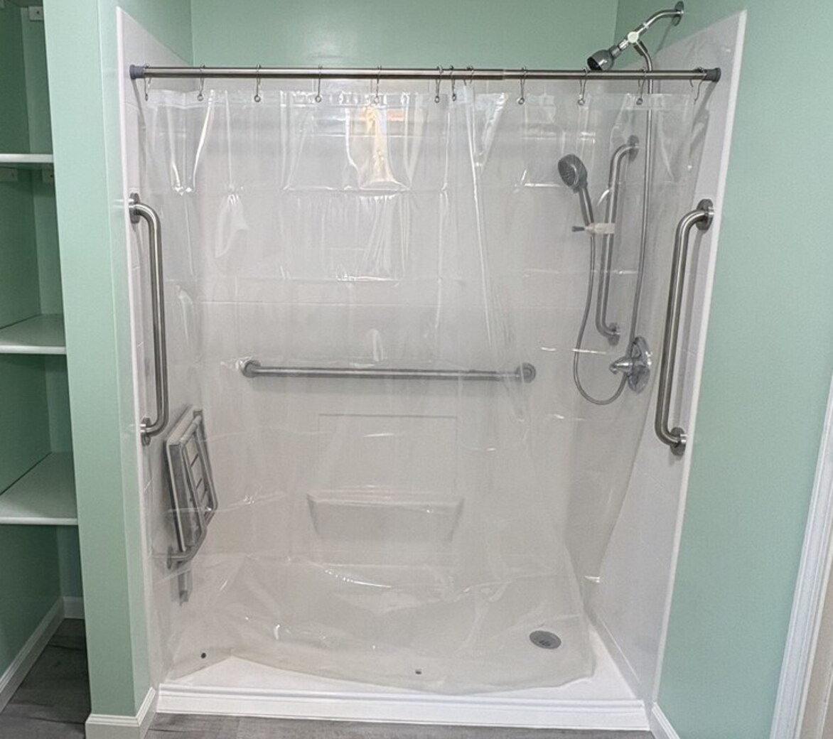 Newly completed accessible bathroom in central Indiana with a low-curb shower, fold-up seat, entry grab bars, and a handheld showerhead on a slide bar